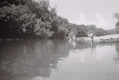Students wading in the Buffalo River, surrounded by lush greenery and calm waters during a summer adventure program.